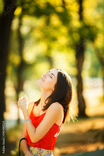 Beautiful woman in red blouse walks in the park