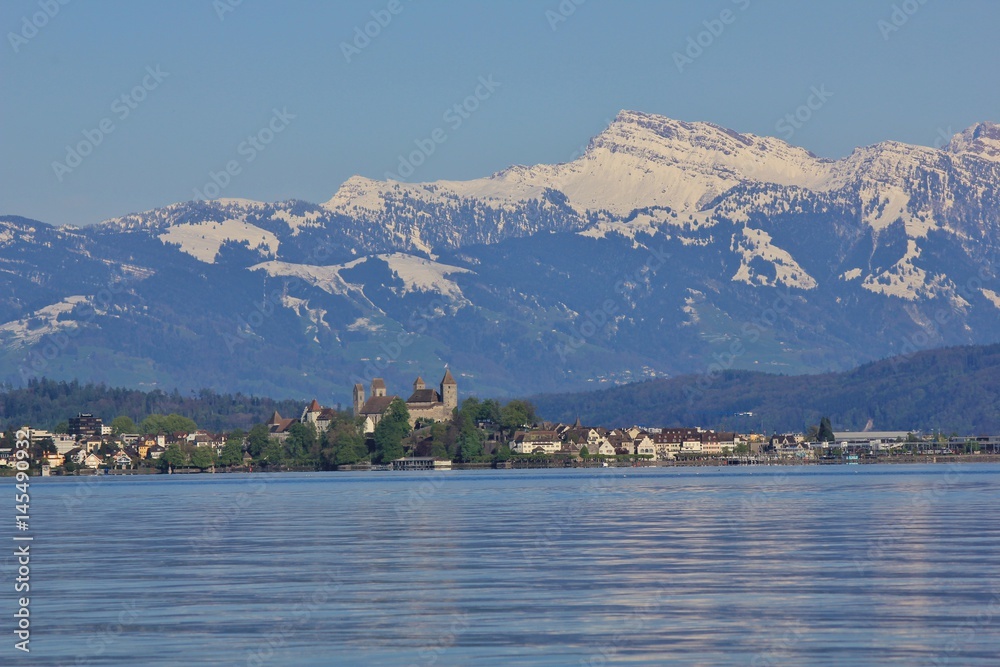 Medieval castle in Rapperswil. Lake Zurichsee and snow capped mountain Grosser Speer.