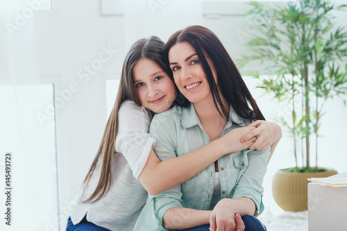 Beautiful mother and her pretty daughter teenager smiling and posing at home