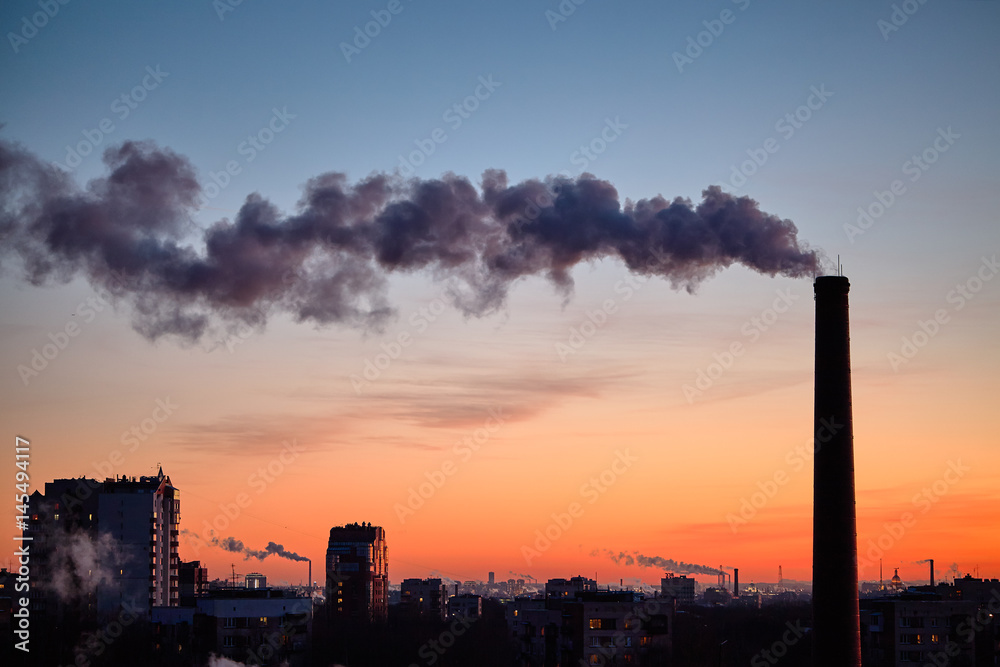 Smoke from industrial chimneys at sunset over the metropolis.