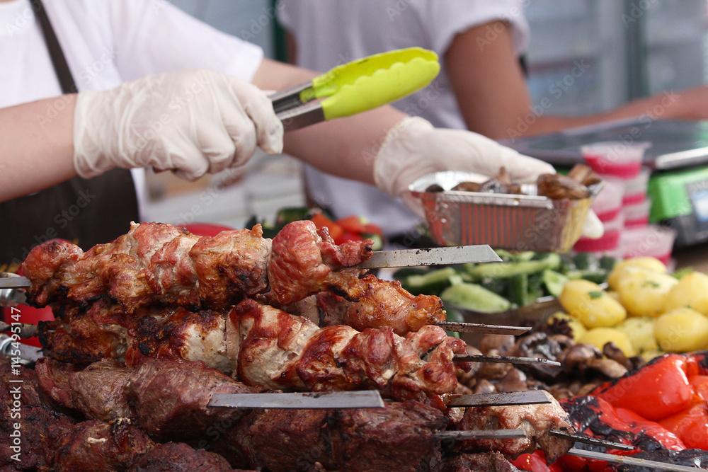 Seller at the counter with shish kebab and vegetables. Food