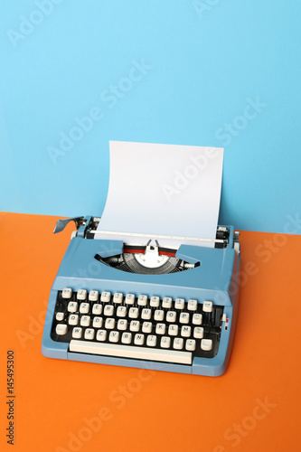 Vintage blue typewriter over a pastel background.