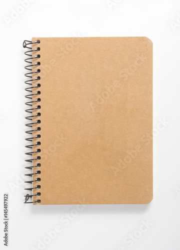 Top view of closed spiral blank recycled paper cover notebook on white desk background