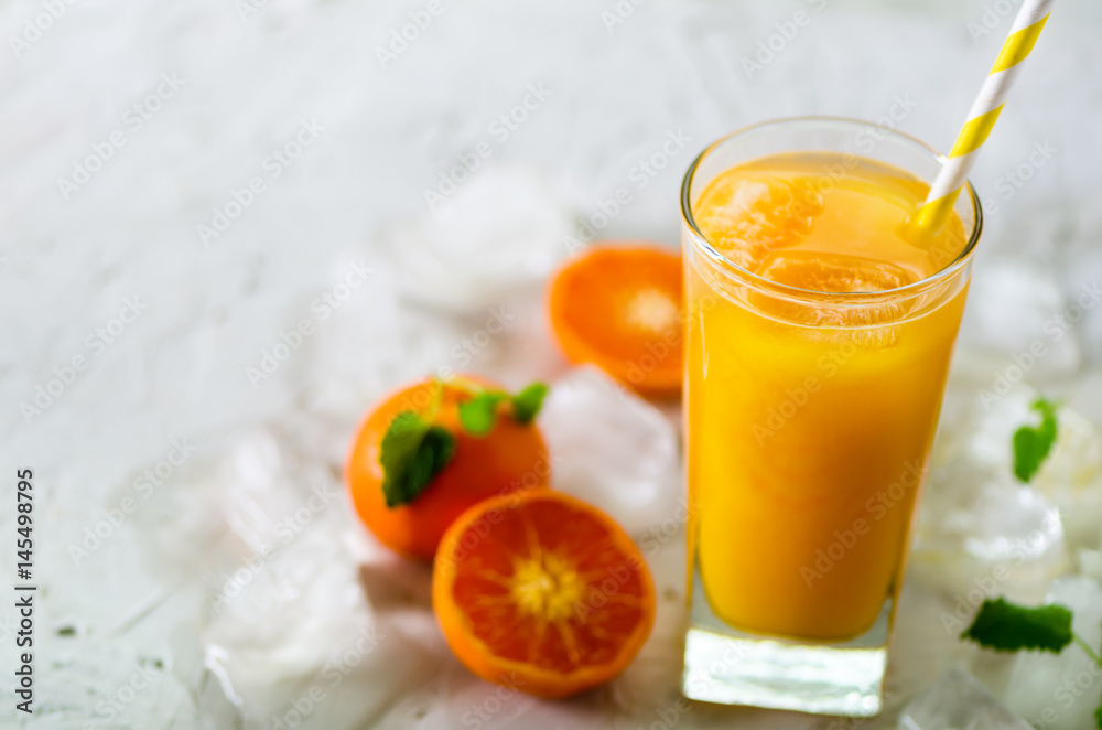 Fresh tangerine juice in glass on white concrete background. Orange fruits with ice, mint. Cold beverage for hot summer day. Copyspace. Fresh tangerine juice in glass on white concrete background. Orange fruits with ice, mint. Cold beverage for hot summer day. Copyspace.