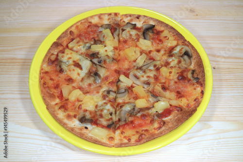 Vegetarian pizza served on a yellow plate on wooden table 