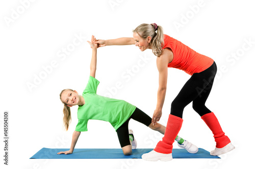 Trainer teaches a little girl to perform an exercise on the mat on a white background