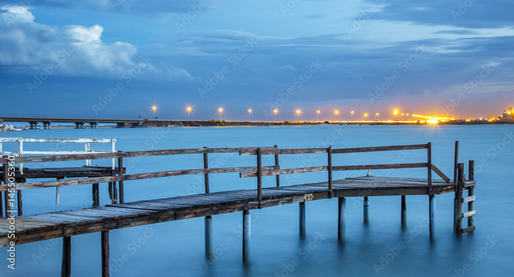 Old Jetty on a River with City Lights in the Background