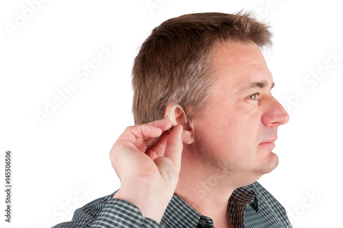 Man inserting a hearing aid into ear