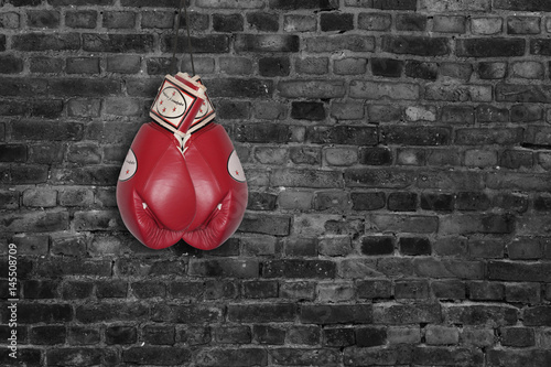 red boxing gloves on a brick wall background © AlexZlat