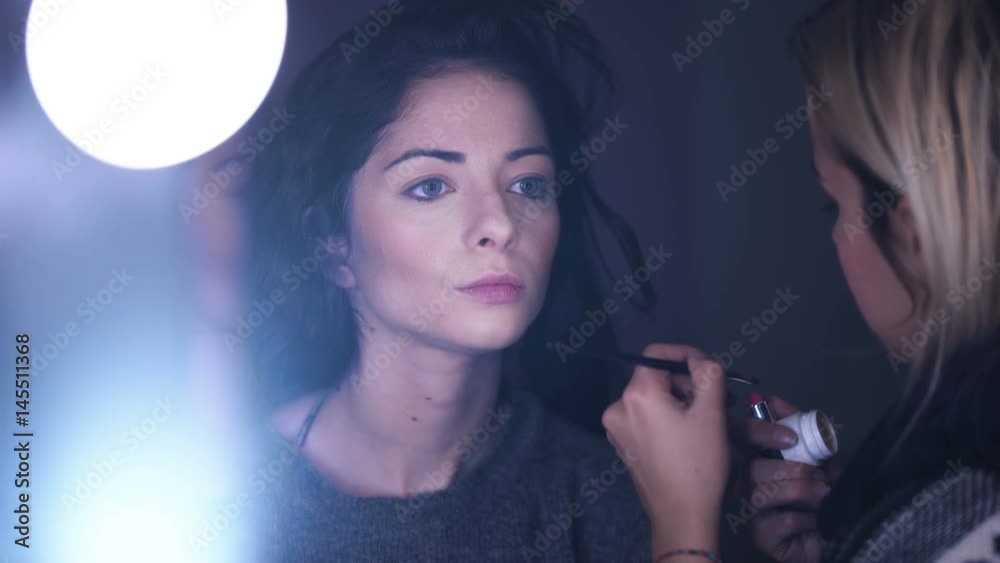 makeup artist making up lipstick on young woman on set makeup artist making up lipstick on young woman on set