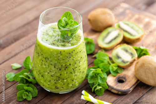 Fresh green kiwi smoothie with mint and honey, healthy organic drink on wooden table