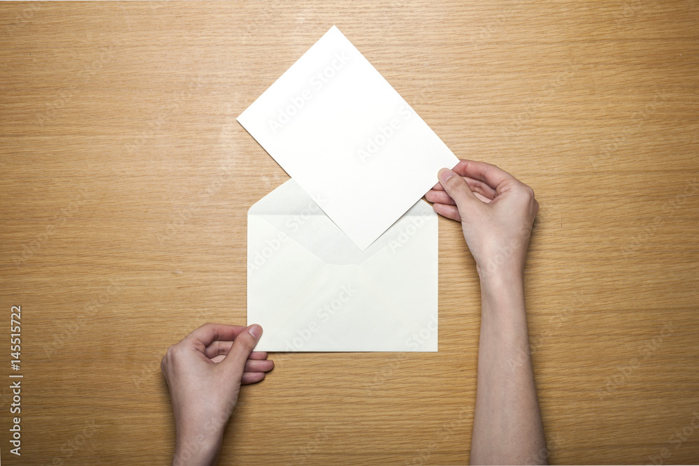 woman hand hold a white envelope on the wood table(background) woman hand hold a white envelope on the wood table(background)