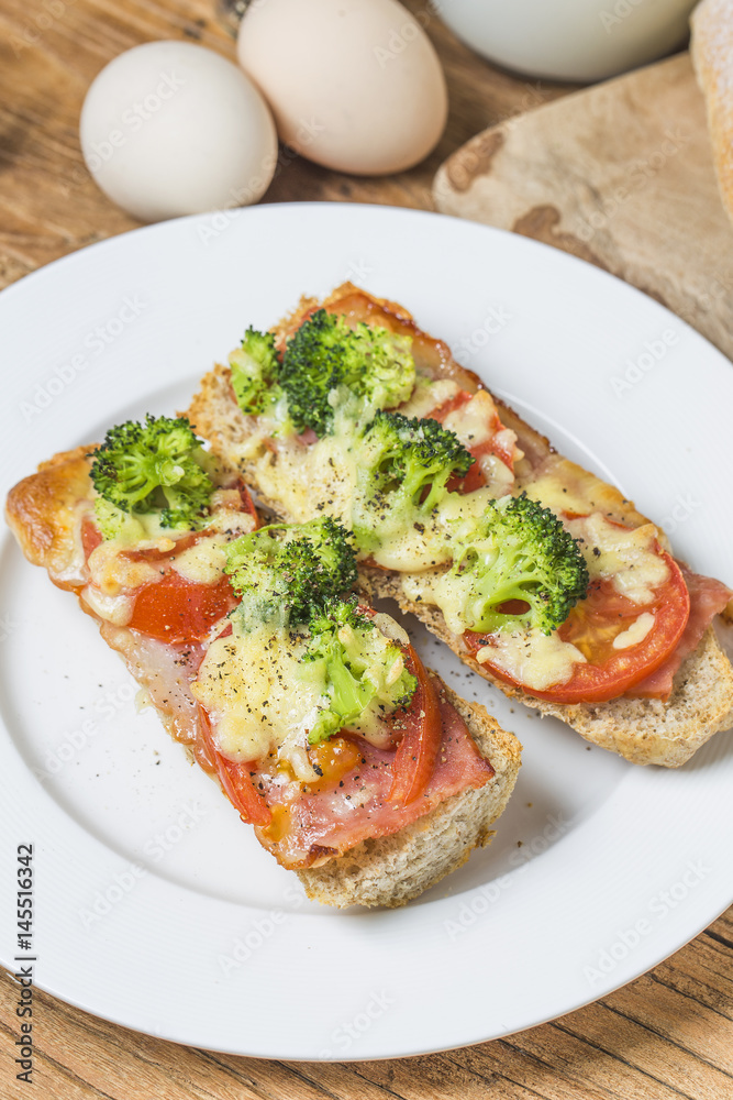 open sandwich with prosciutto, mozzarella and tomatoes on kitchen table, shallow focus open sandwich with prosciutto, mozzarella and tomatoes on kitchen table, shallow focus