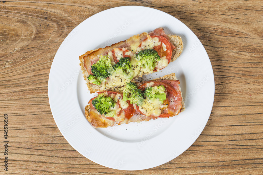 open sandwich with prosciutto, mozzarella and tomatoes on kitchen table, shallow focus open sandwich with prosciutto, mozzarella and tomatoes on kitchen table, shallow focus