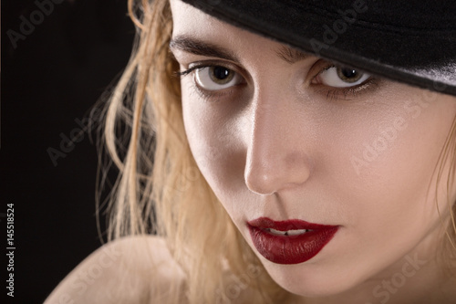 sensual beautiful young woman in hat on black background