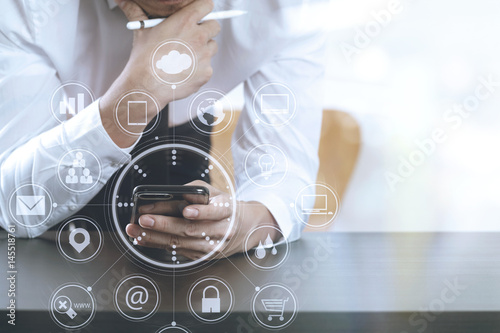 close up of businessman working with smart phone on wooden desk in modern office