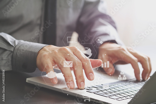 close up of businessman working with laptop computer on wooden desk in modern office with virtual icon diagram