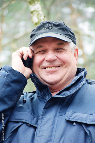 Senior caucasian man speaking by mobile phone in the forest