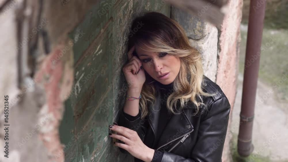 Sad and upset blond woman leaning against the wall Sad and upset blond woman leaning against the wall