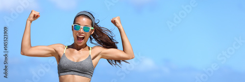 Strong fitness woman banner crop with copyspace on sky. Girl in sunglasses showing off muscular arms flexing biceps for fun on beach. Weight loss success concept.