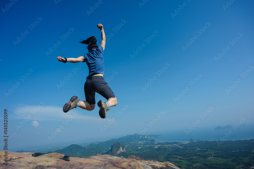 jumping on rocky mountain peak, freedom, risk, challenge, success concept jumping on rocky mountain peak, freedom, risk, challenge, success concept
