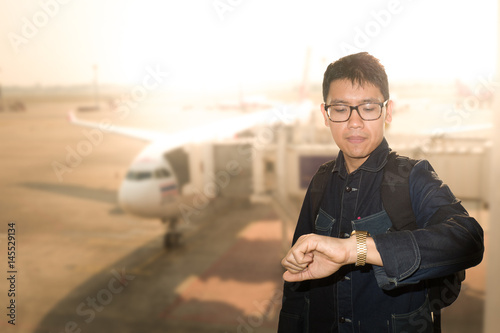 Asian man is serious watching his watch in flight delay concept. photo