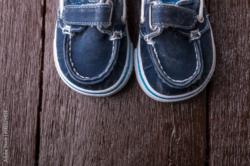 Blue boat shoes on brown wooden background. Boy footwear. Top view. © bondarillia