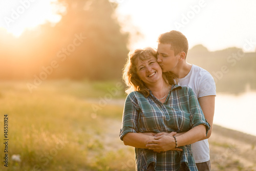 Young adult boy kissing his mother with love