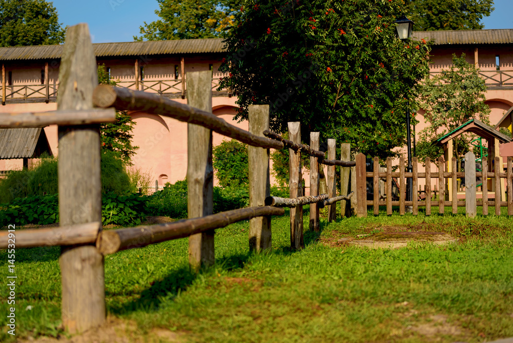 Decorative fence of logs on a green lawn Decorative fence of logs on a green lawn