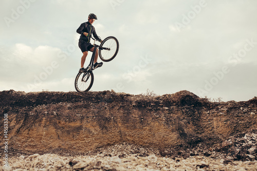 Biker jumping from rock