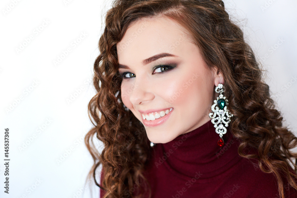 Portrait of a young woman with an evening make-up and hair-style. Laughing girl with curly hair