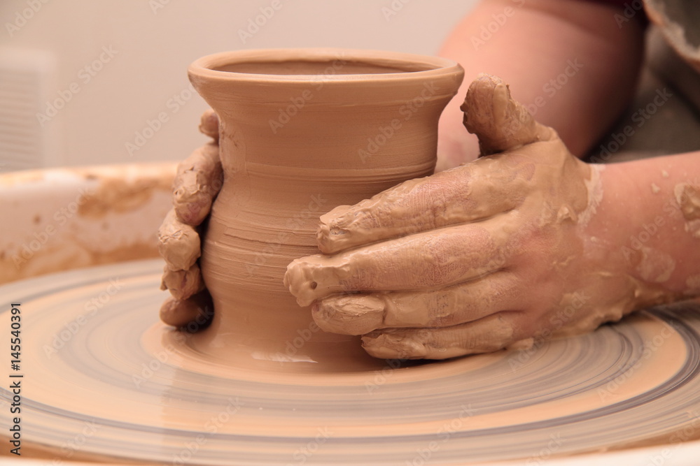 Hands of a potter, creating an earthen jar on pottery wheel. Hands of a potter, creating an earthen jar on pottery wheel.