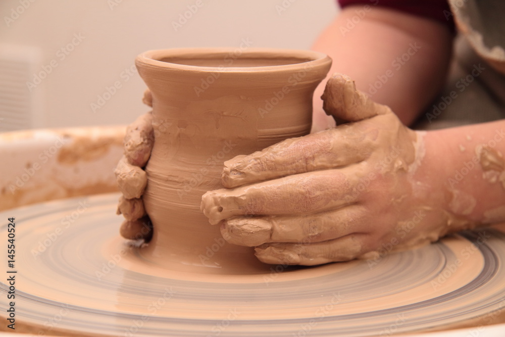 Hands of a potter, creating an earthen jar on pottery wheel. Hands of a potter, creating an earthen jar on pottery wheel.