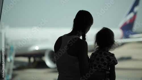 Silhouettes of mother ahd daughter with airplane on the background photo