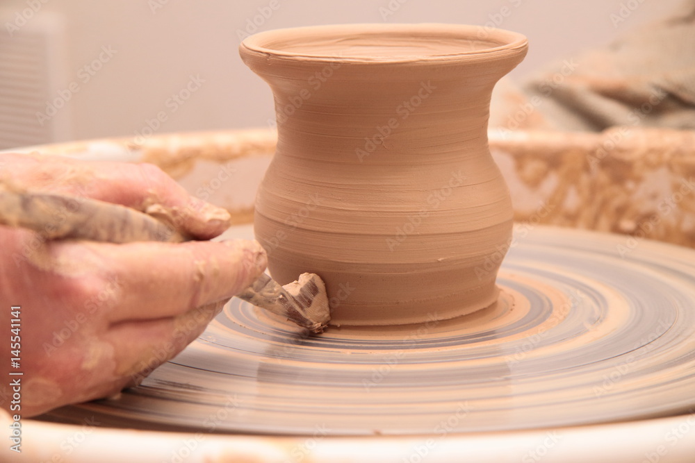 Hands of a potter, creating an earthen jar on pottery wheel. Hands of a potter, creating an earthen jar on pottery wheel.
