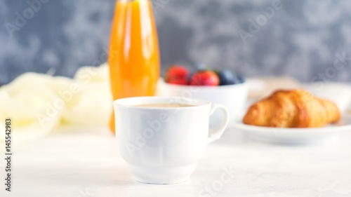 Cup of coffee, juice, fresh berries and croissants on white background. Morning breakfast