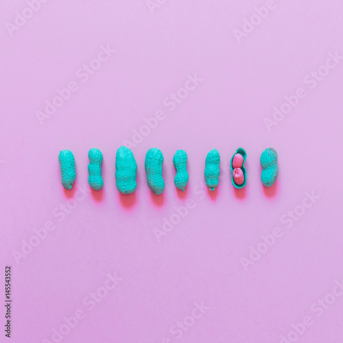 fashion flat lay set of peanuts painted in blue with one peeled peanuts with pink core in line. minimal concept of snacks..