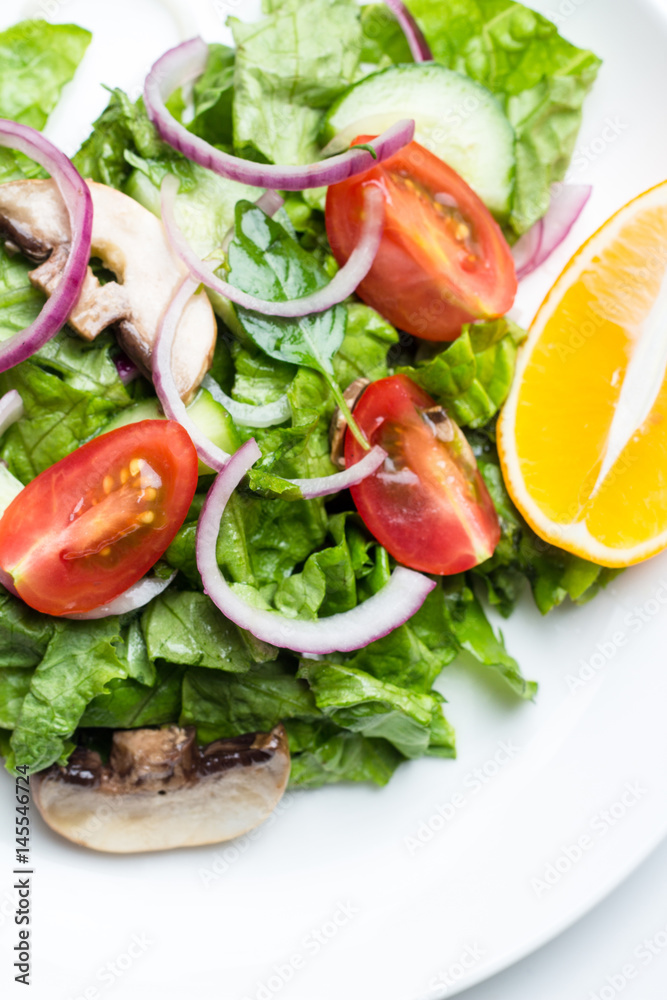 Salad of vegetables and champignons, lemon on white dishes close-up. Salad of vegetables and champignons, lemon on white dishes close-up.