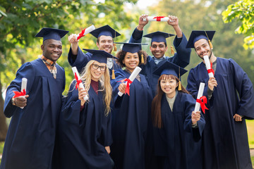 happy students in mortar boards with diplomas