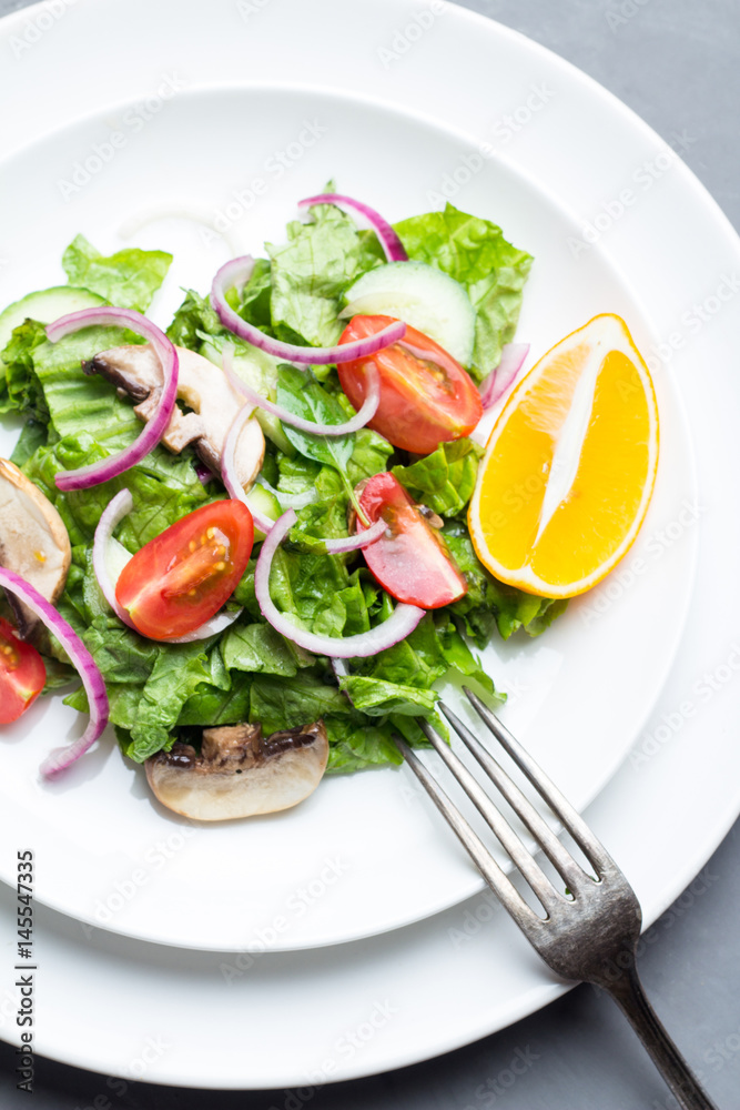 Vegetable salad with mushrooms on a white plate close-up. Vegetable salad with mushrooms on a white plate close-up.