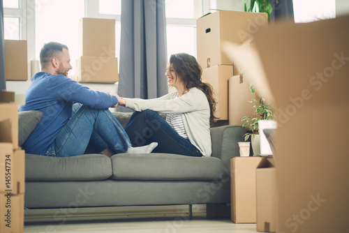 Caucasian couple sitting on sofa and holding hands surrounded by boxes