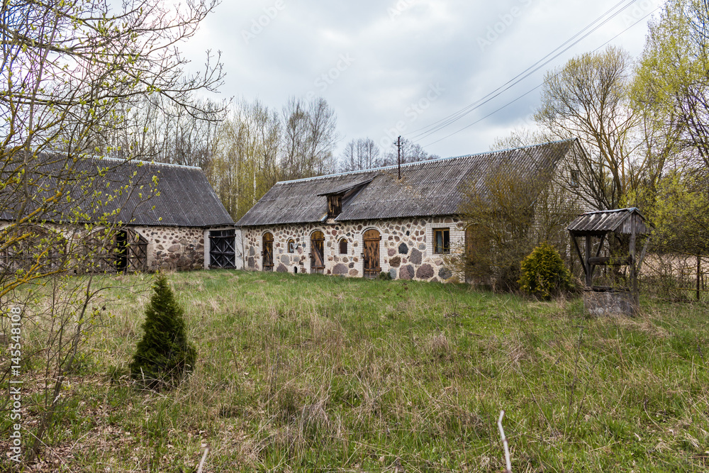 The yard of an abandoned village farm. Stone barns and a well. Spring in the Region Podlasie, Poland. The yard of an abandoned village farm. Stone barns and a well. Spring in the Region Podlasie, Poland.