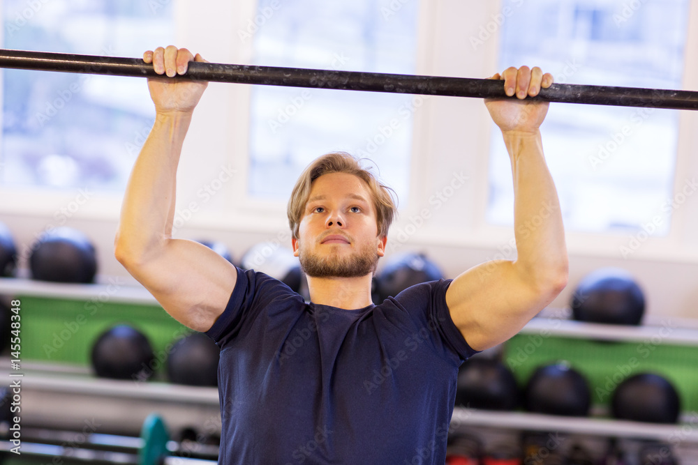 Naklejka premium man exercising on bar and doing pull-ups in gym