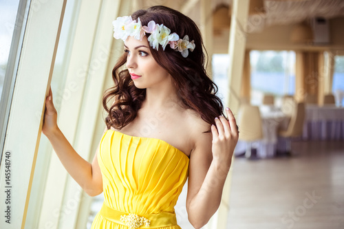 Beautiful young woman with long hair in a summer day. bridesmaid in yellow dress in a sea restaurant photo