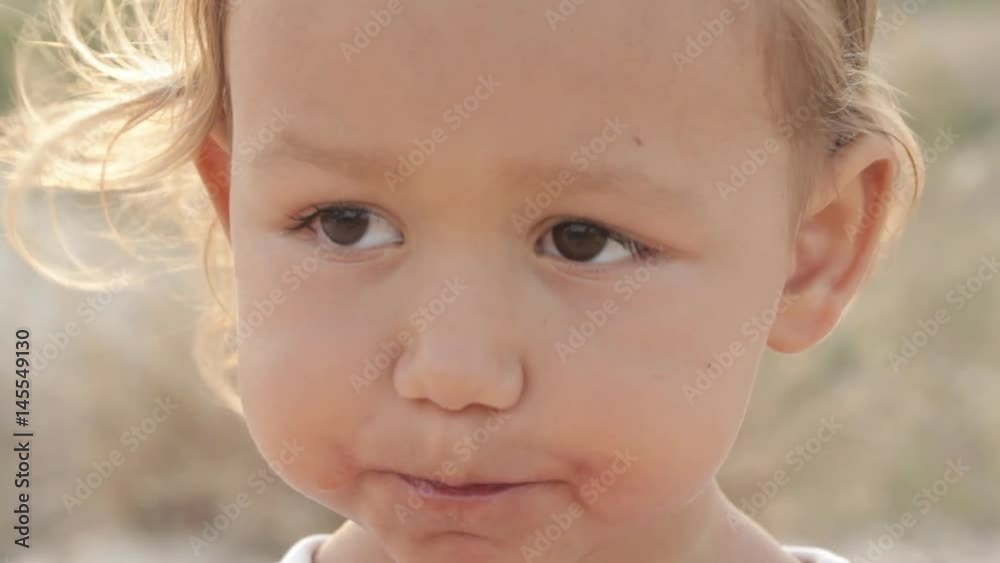 Close-up portrait of small cute baby girl eat red watermelon at sunrise