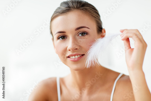Fotografia beautiful woman with feather touching her face