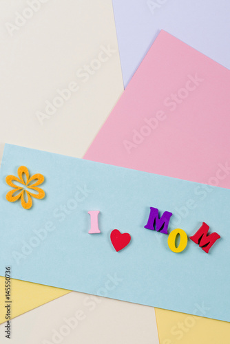 Mothers Day concept. I love mom spelled with colorful wooden letters on paper background.