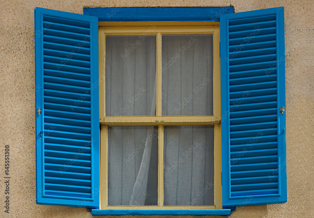 Blue  casement, yellow framed windows of an old but well-kept house