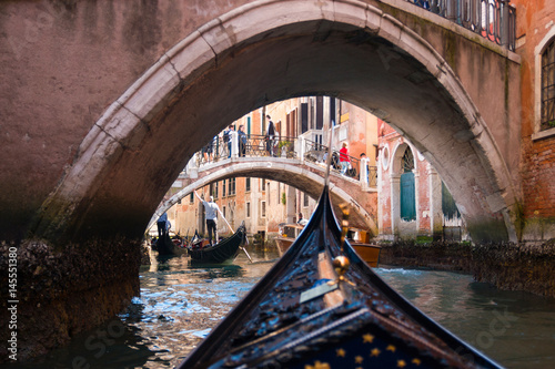 View from gondola under old bridge in street of Venice