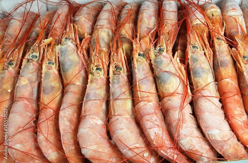 Frozen langoustines lie in row in cardboard box. Closeup © Alexandrova Elena